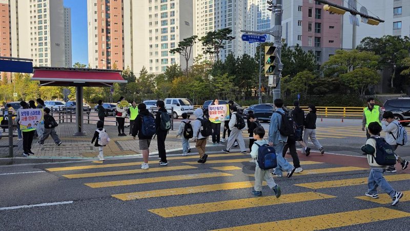 참여자들이 어린이들과 함께 건널목을 건너며 안전한 보행 방법을 안내하고 있다.