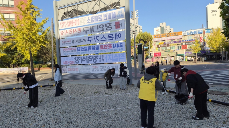 주민자치회 위원과 대학생들이 거리에서 쓰레기를 수거하며 환경정비를 하고 있다.