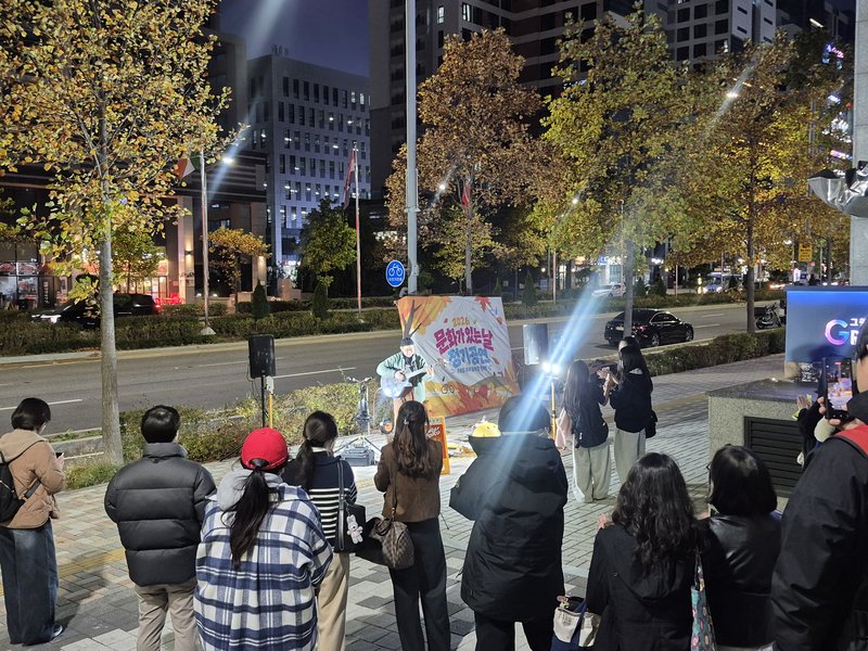 퇴근길 주민들이 오가는 길목에서 아티스트가 라이브 연주를 하고 있다.